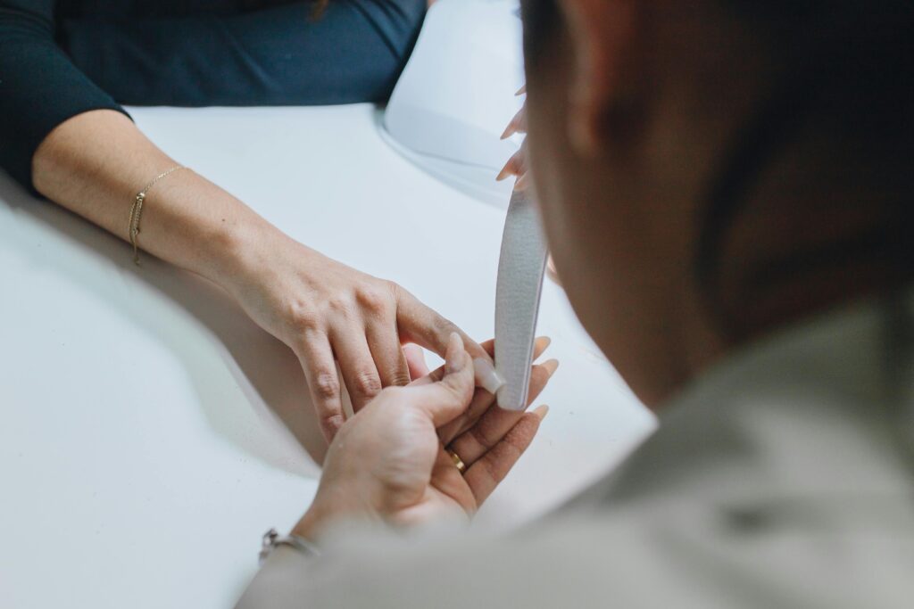 Close-up of a manicurist filing nails during a professional manicure session in a salon.